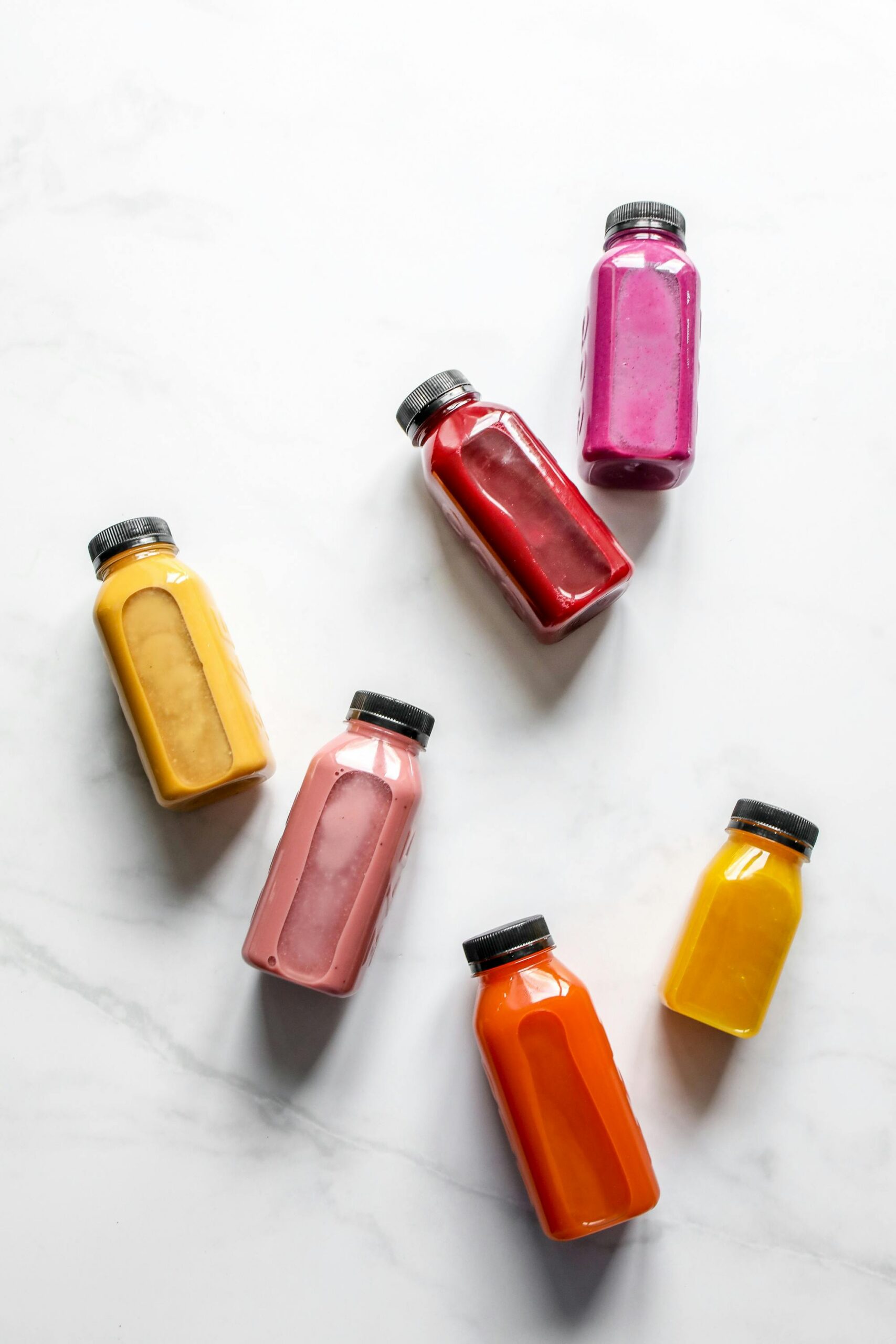 A vibrant array of healthy canebar juice in bottles on a clean marble surface, perfect for a health-conscious lifestyle.